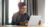 A woman sat at a table on a laptop, with a coffee cup and stack of papers each side.